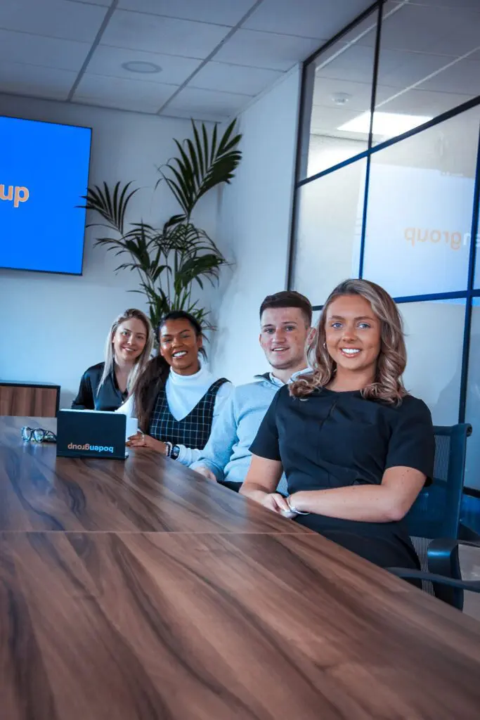 A picture of four members of the Boden Group engineering team, sitting around a large conference table in a boardroom, with a projector screen visible in the background, indicating they are discussing a presentation.